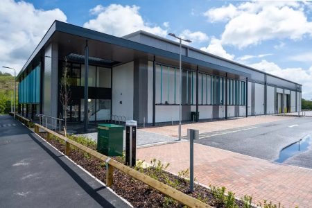 A modern commercial building featuring large windows and a flat roof, set against a clear blue sky.